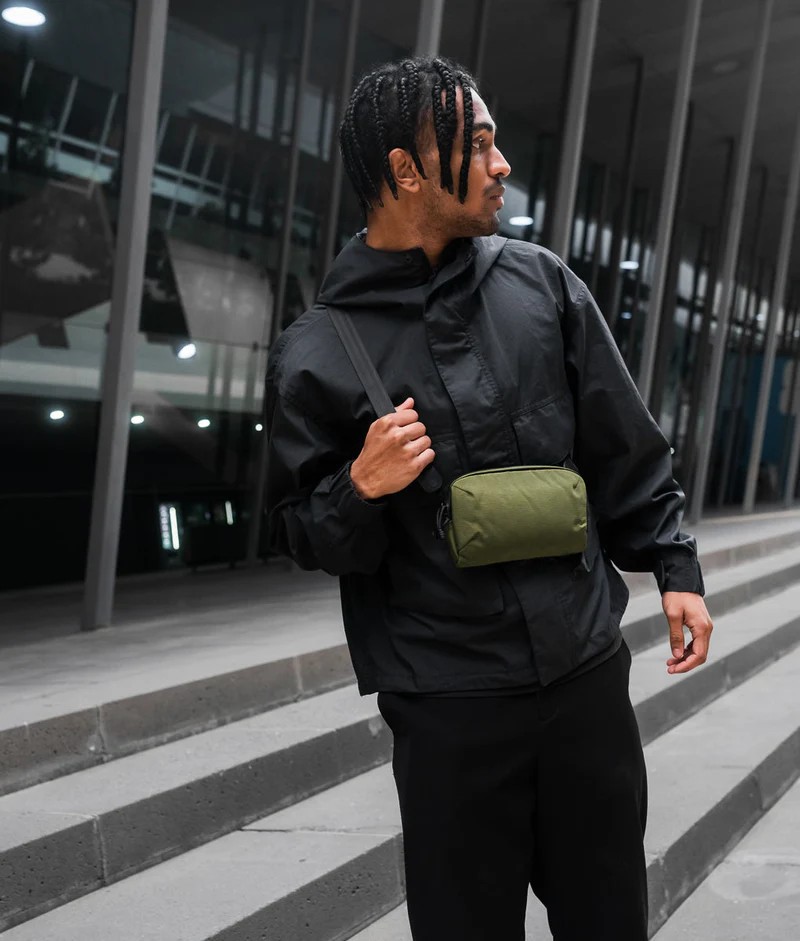 Alpaka Flight Pouch Pro Green nošená přes rameno na letišti