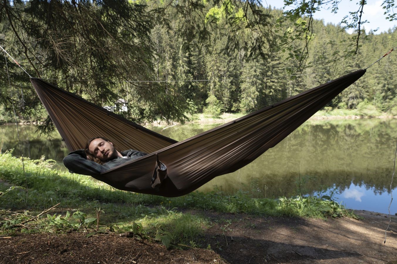 Cocoon hamaka Ultralight Hammock storm blue – muž odpočívá v hamace u jezera