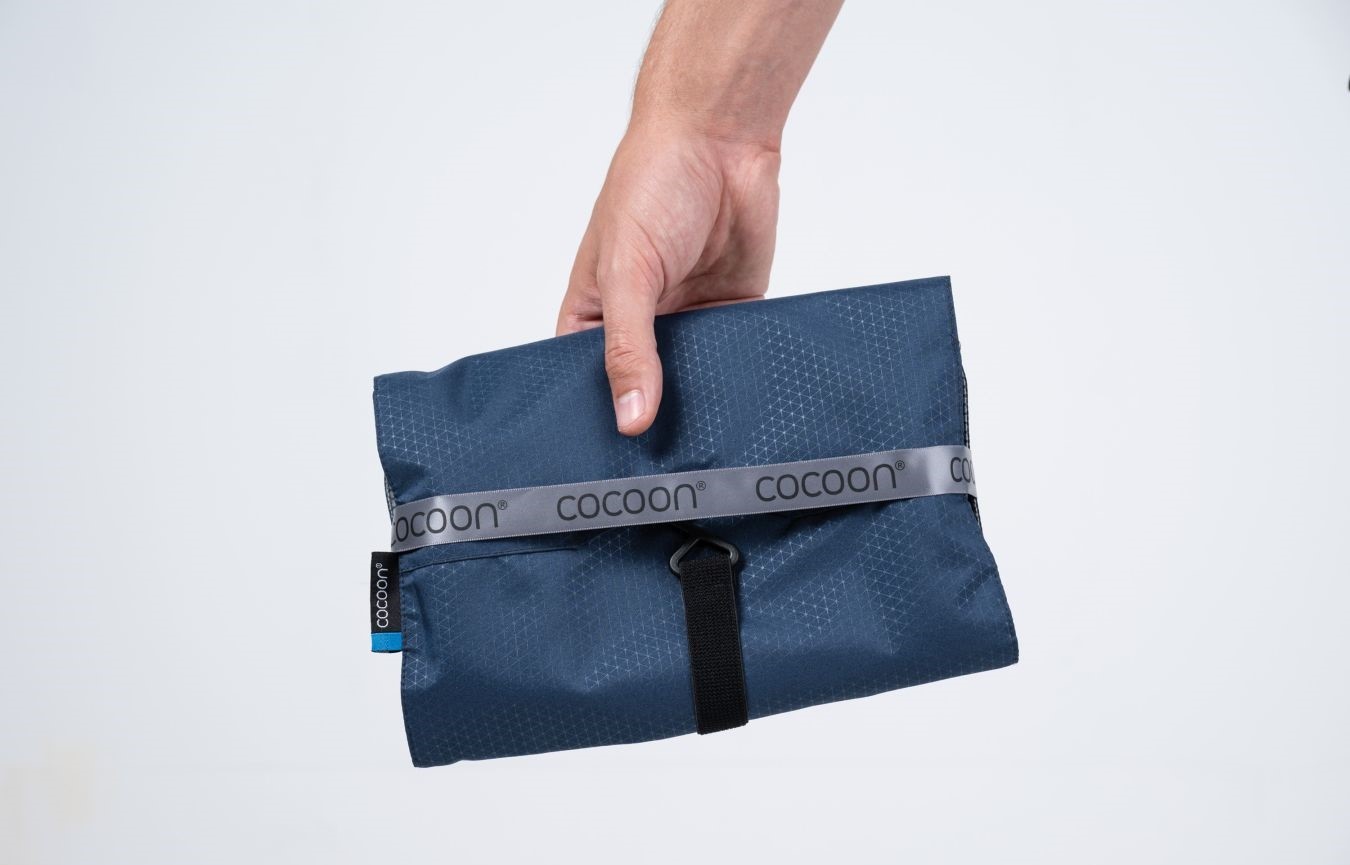 Cocoon toaletní taška Hanging Toiletry Kit Minimalist galaxy blue – složená toaletní taška v ruce